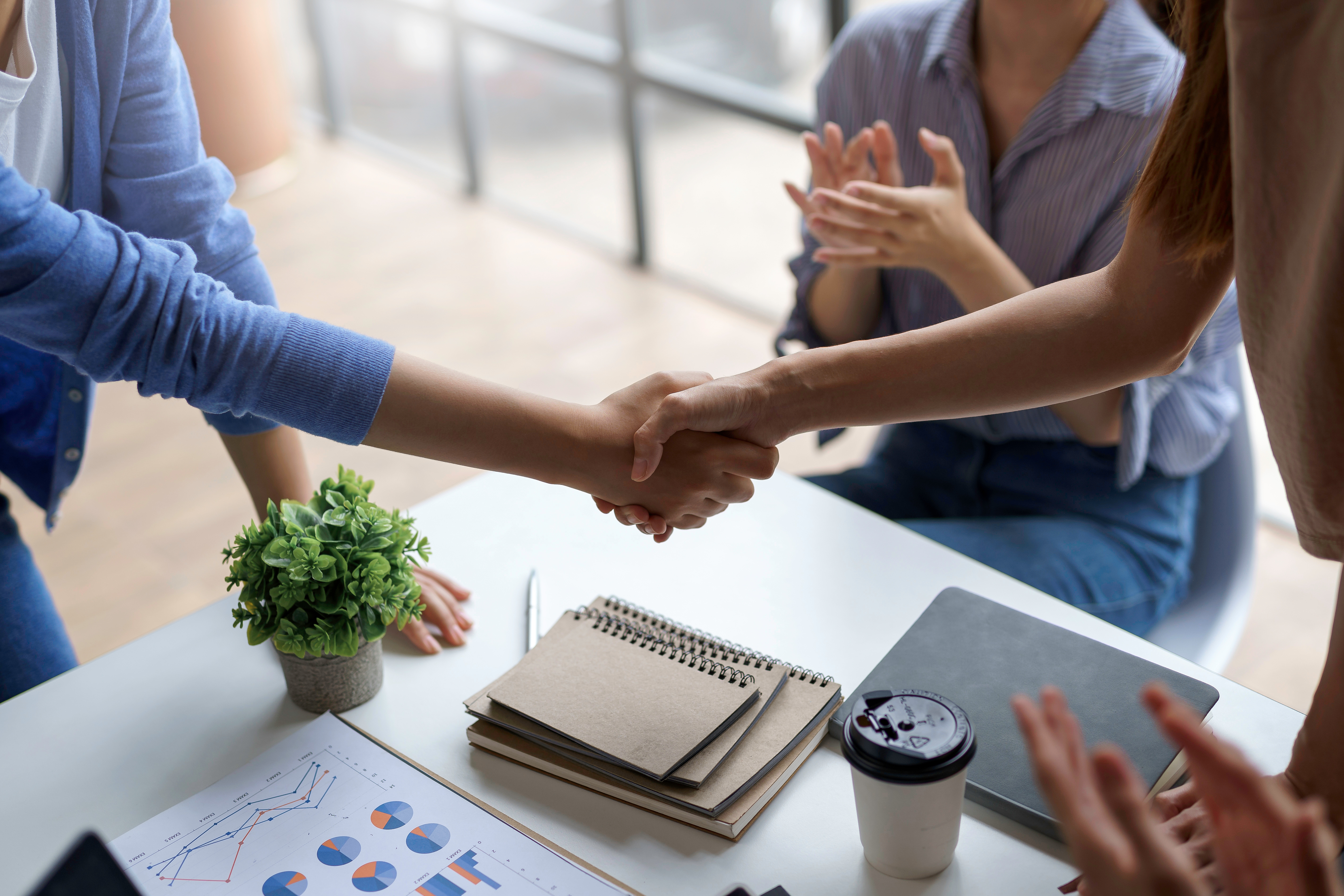 A group of Asian business people handshake to make a contract business agreement to start a new business.